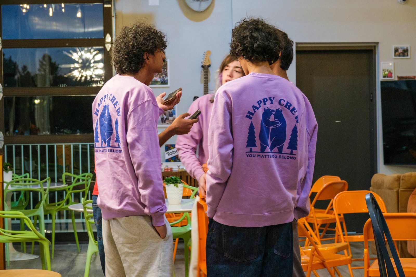 Two student leaders from behind, the Happy Crew bear on their sweatshirts